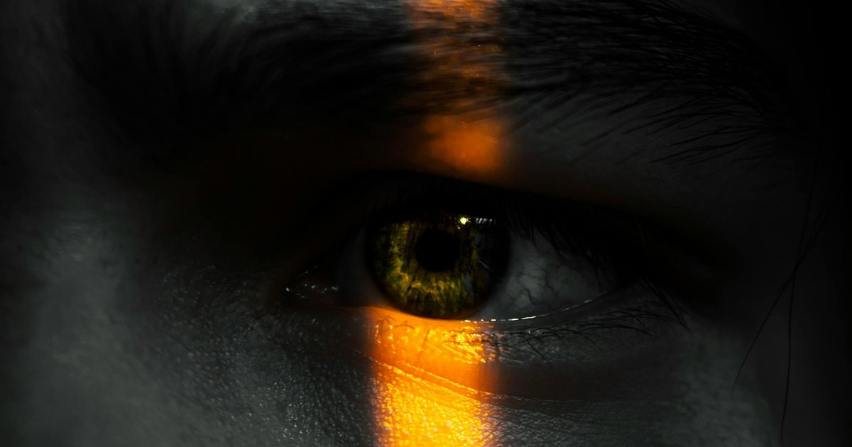 Close-up of an eye with vivid contrast of light and shadow, evoking mystery and introspection.