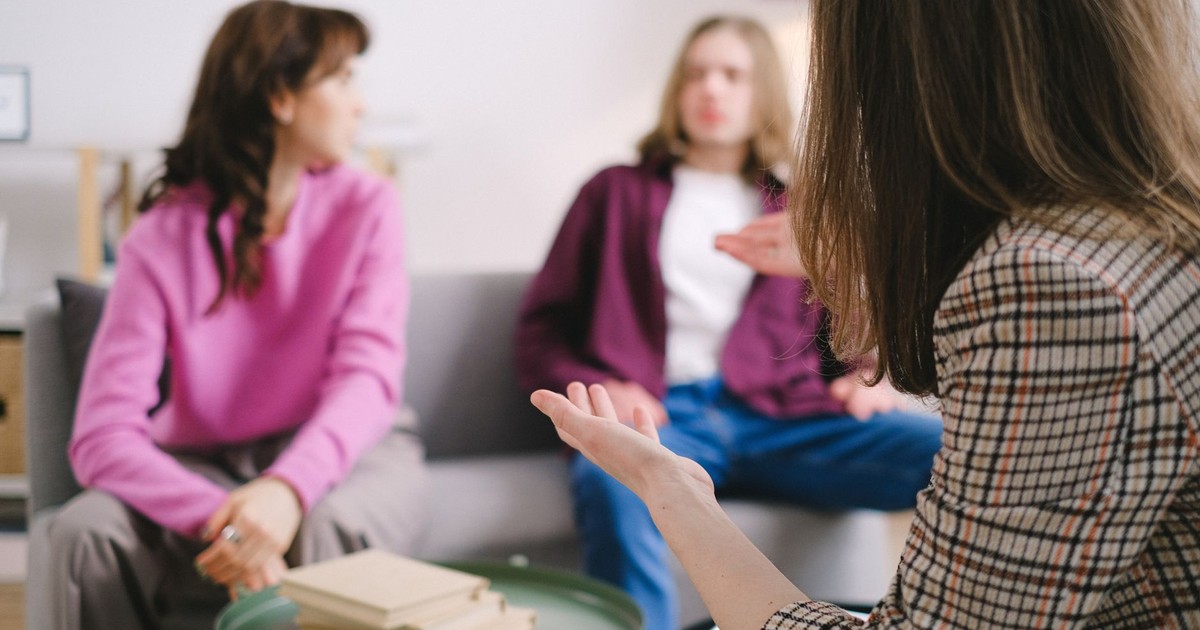 Engaged counseling session with three adults discussing together in a cozy indoor setting.