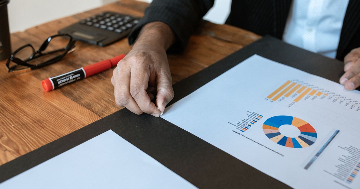 Close-up of a business setting with charts, documents, and a hand pointing.