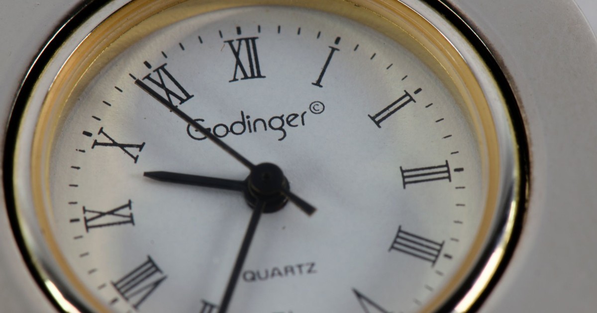 Detailed close-up of a Godinger quartz clock with classic Roman numerals and clock hands.