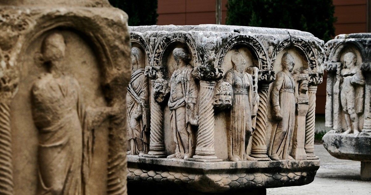 Detailed stone carvings of ancient Roman figures displayed outdoors in a museum setting.