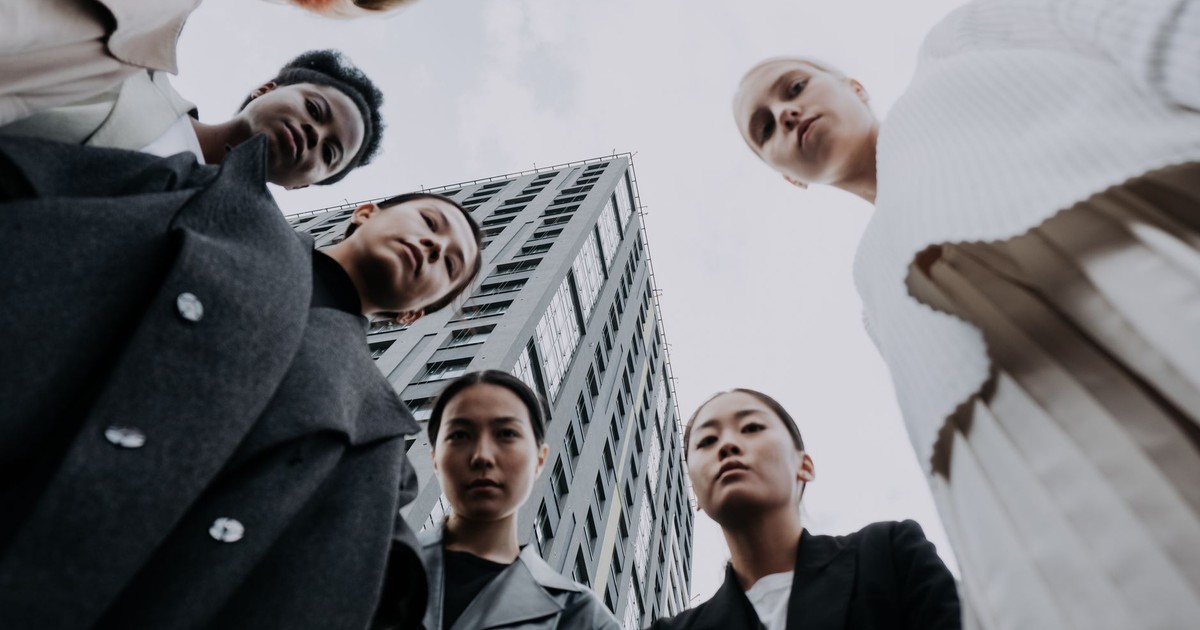 Low angle shot of a diverse group in fashionable attire against an urban backdrop.