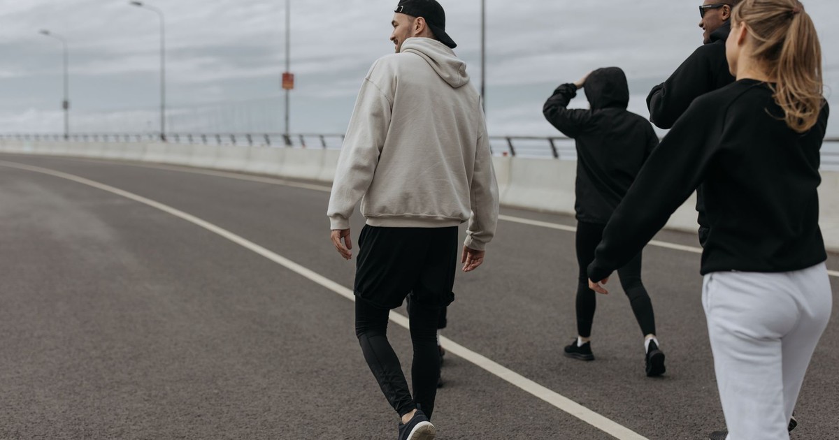 A group of four adults walking for exercise on a city road during a cloudy day.