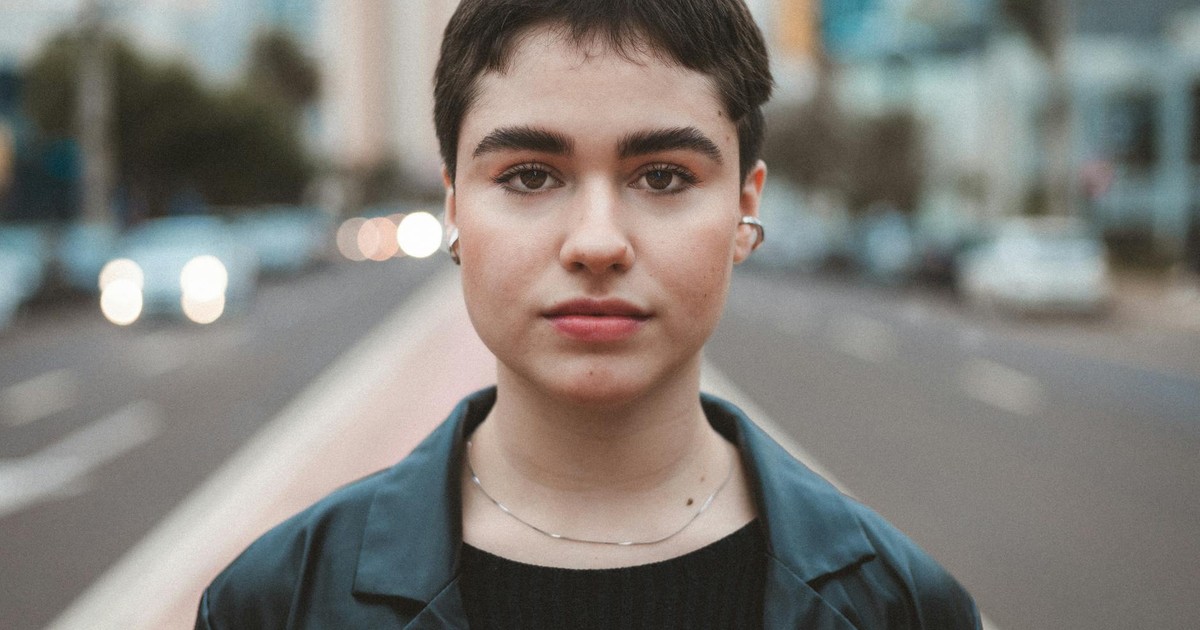 Portrait of a young woman with short hair standing confidently on an urban street.