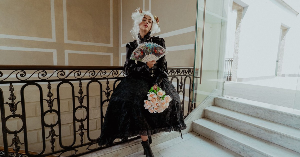 A woman in vintage attire poses with a fan and bouquet on an elegant staircase in Mexico City.