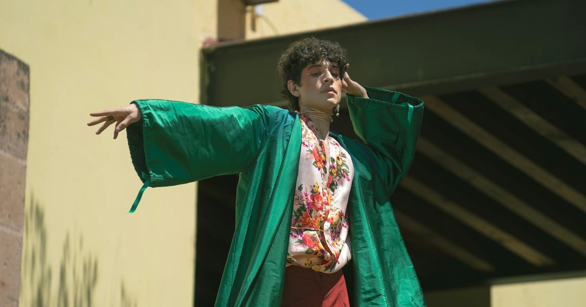 A stylish figure poses outdoors in a vibrant green kimono with floral details under bright sunlight.