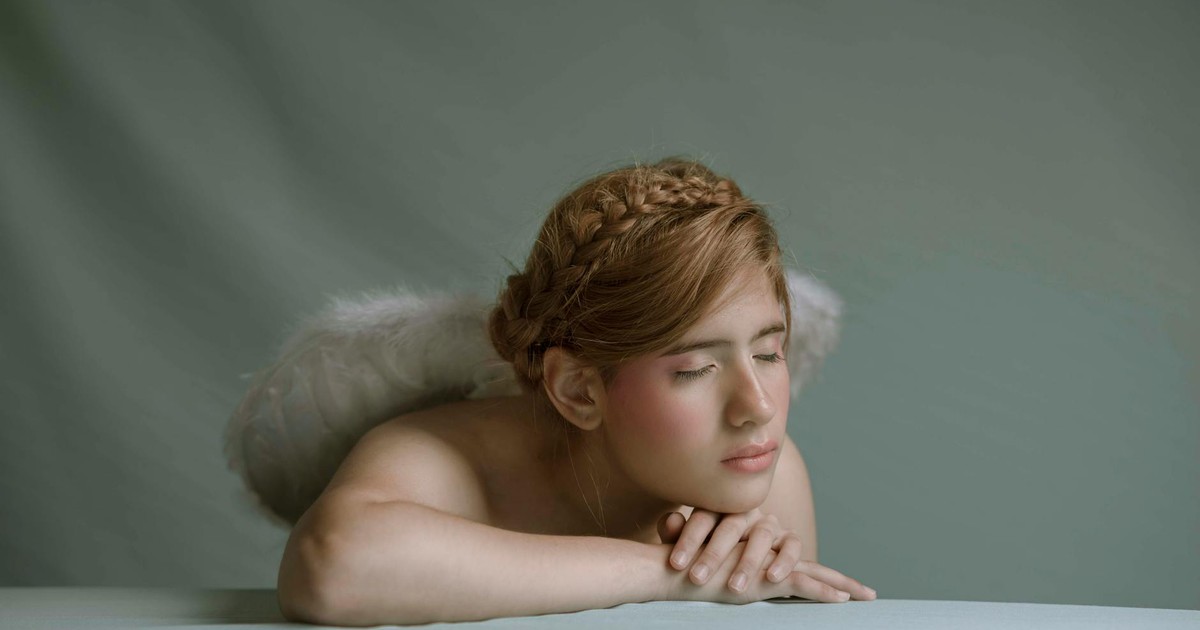 A portrait of a serene angelic figure with closed eyes and wings, embodying tranquility.