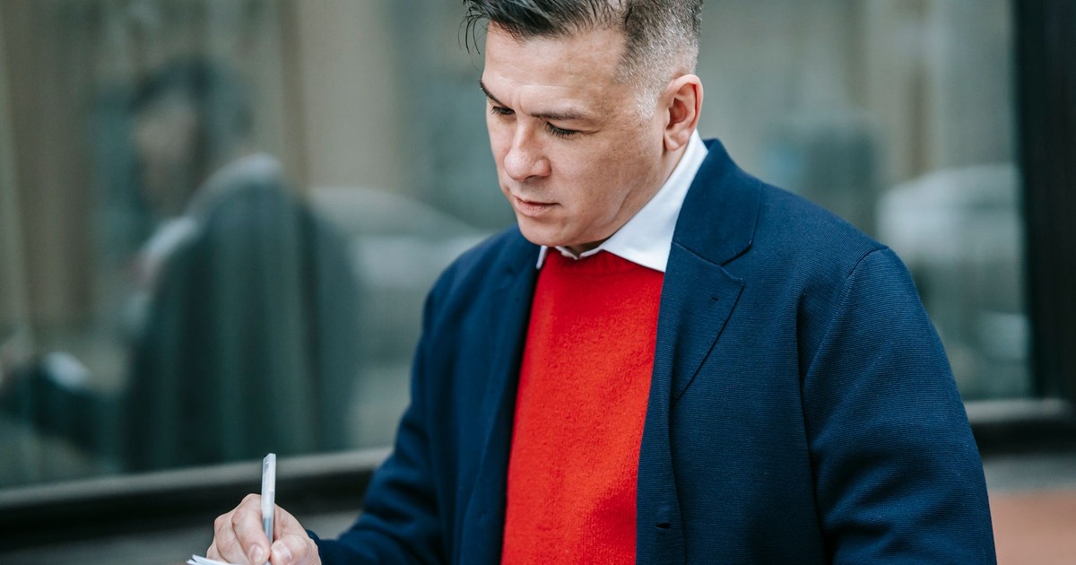Focused professional man jotting down notes outside, reflecting modern business style.
