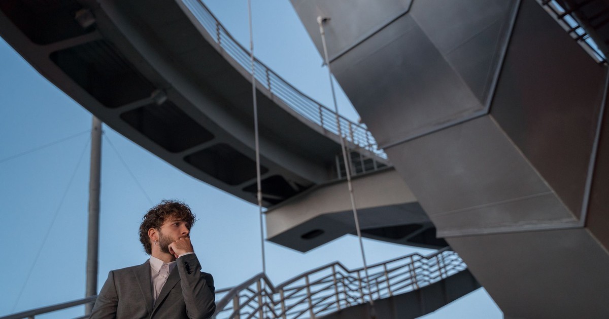 Young man in a suit standing by an architectural marvel, a symbol of modern urban design.