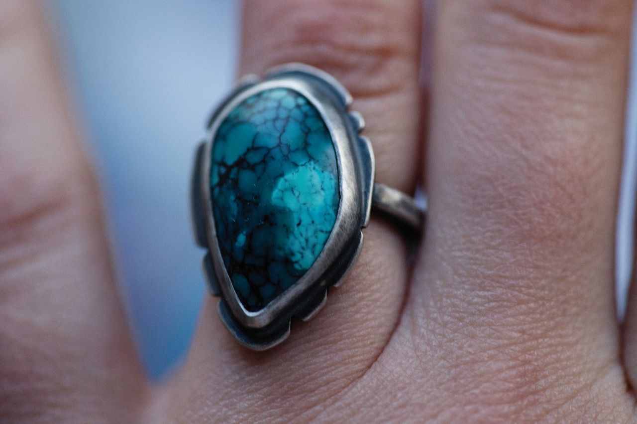 Detailed close-up of a hand adorned with a luxury ring featuring a turquoise stone