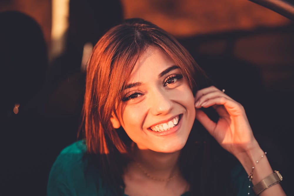 Close-up of a smiling woman with brunette hair in warm lighting, radiating joy and positivity