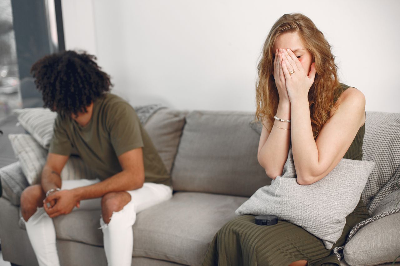 Couple experiencing emotional conflict on a sofa indoors with depth of field effect