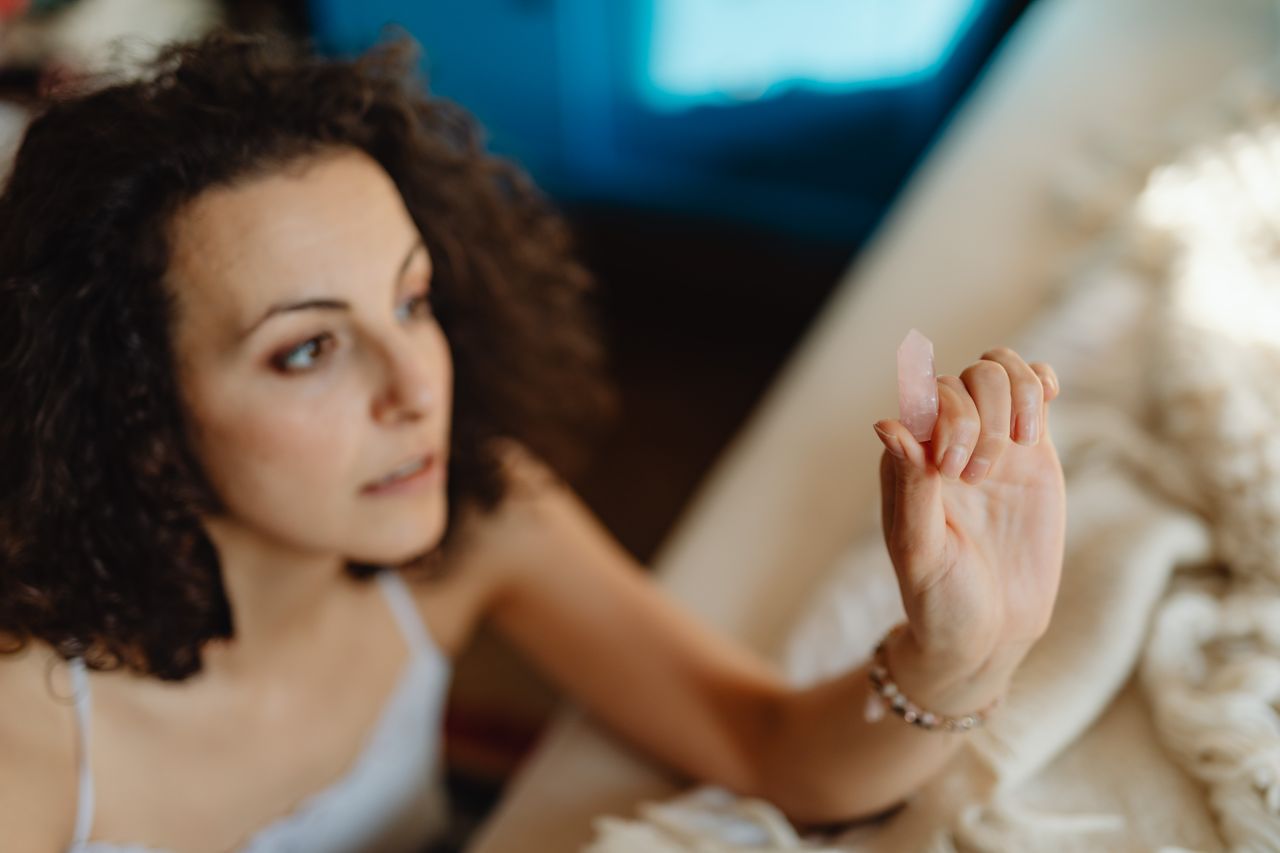 Focused woman holding a healing crystal indoors, embodying relaxation and alternative medicine