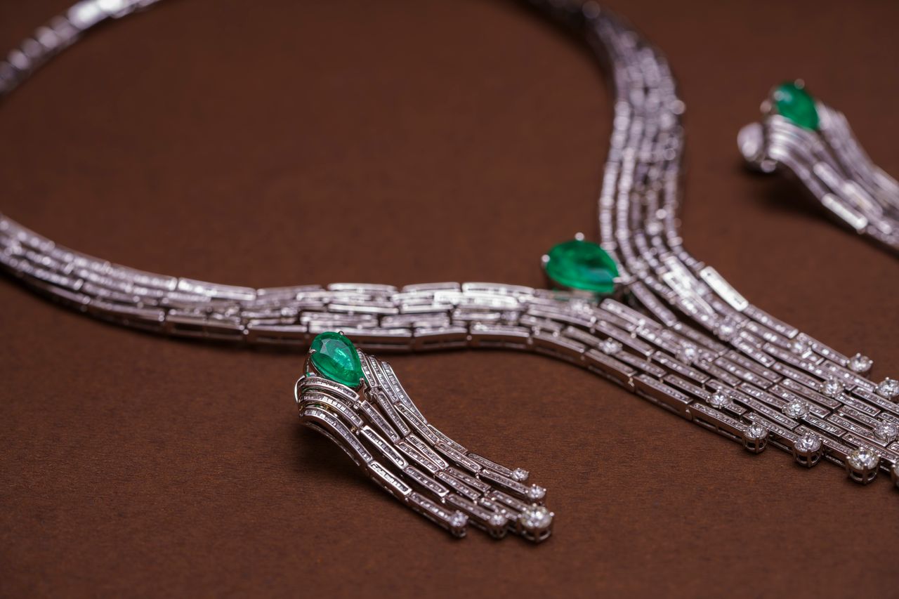 Close-up of a luxurious necklace adorned with diamonds and emeralds on a brown background