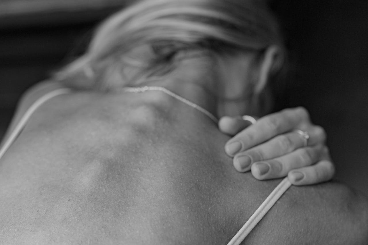 A close-up monochrome image of a woman's back, highlighting skin texture and form