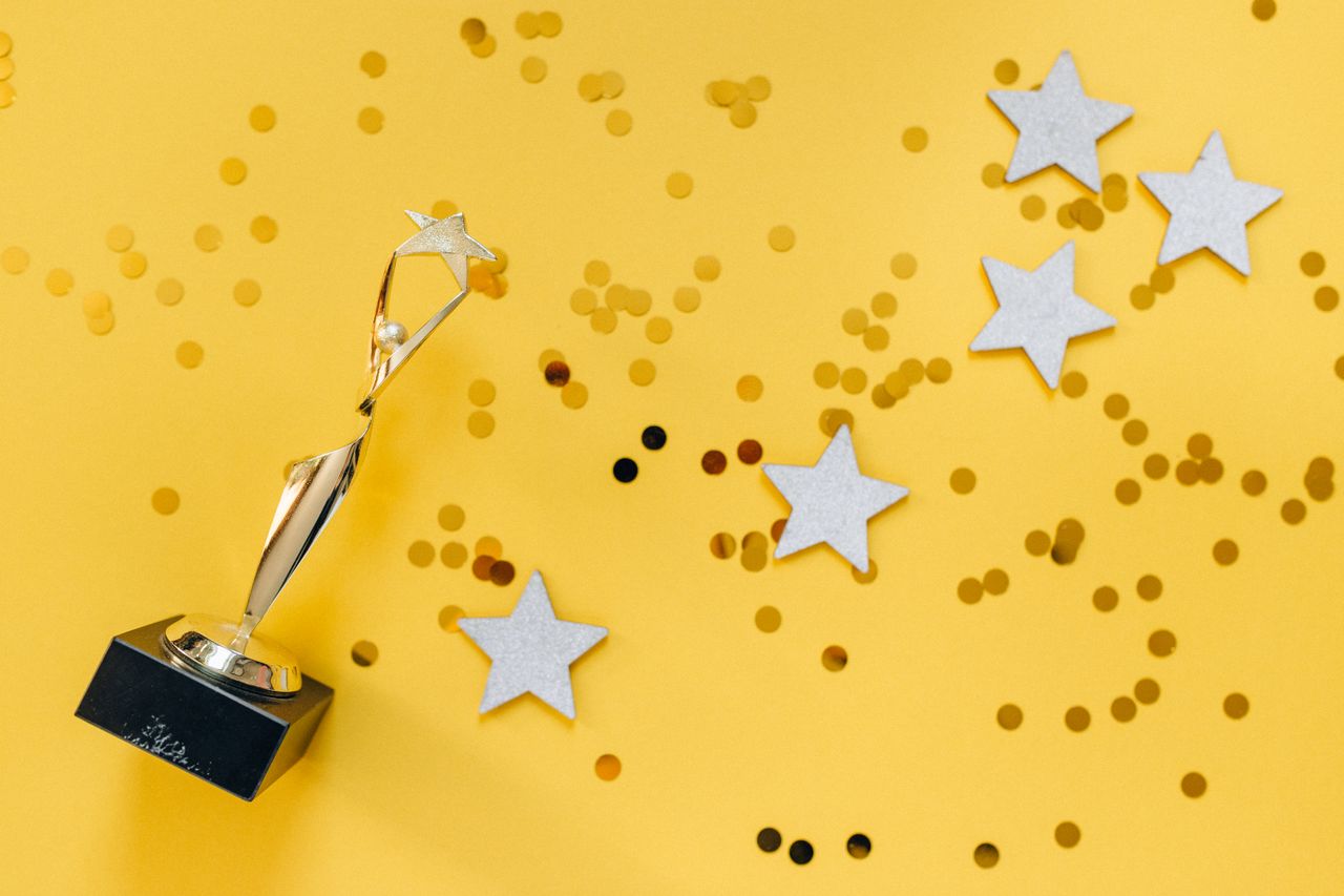 Shiny golden trophy and stars on a vibrant yellow background, symbolizing success and victory