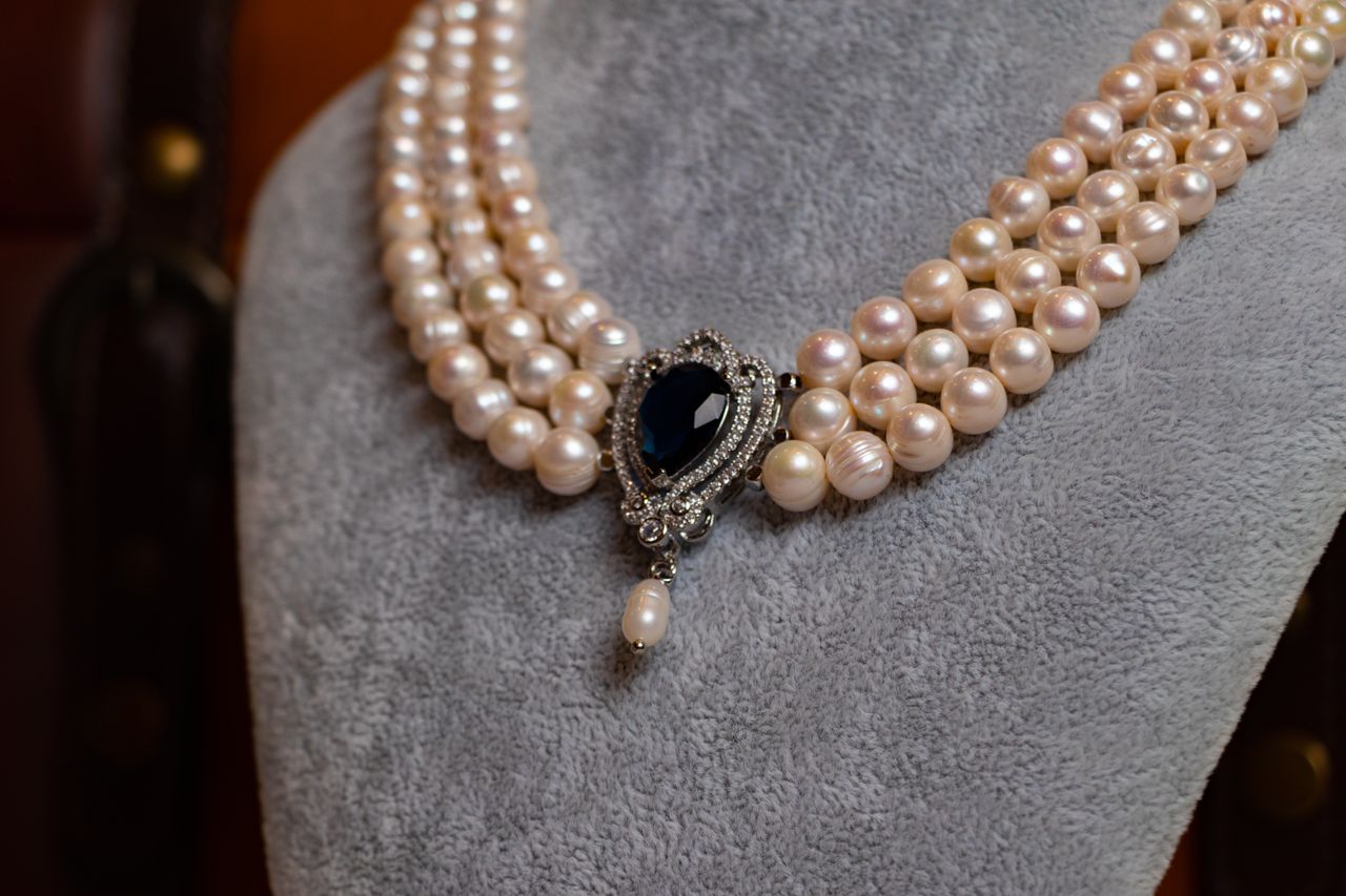 Close-up of a vintage pearl necklace with an ornate sapphire pendant, showcasing luxury and elegance