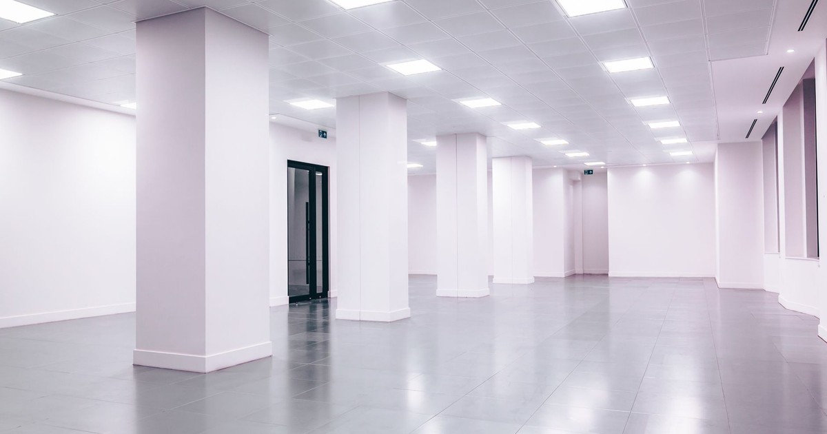 Wide-angle view of a modern minimalist white office space with clean lines and ample lighting.