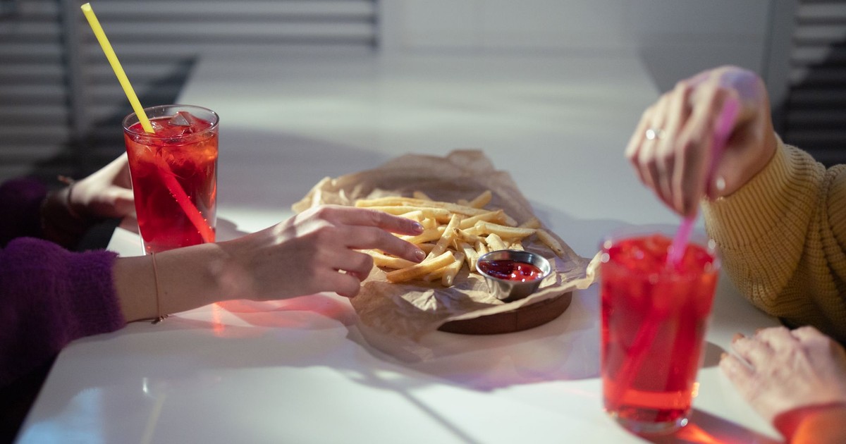 Two people enjoy drinks and french fries at a cafe table.