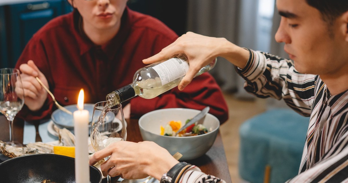 Friends enjoying a cozy dinner at home, sharing wine and conversation.