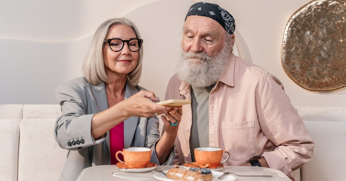 A happy senior couple shares coffee and pastries at a cozy café.
