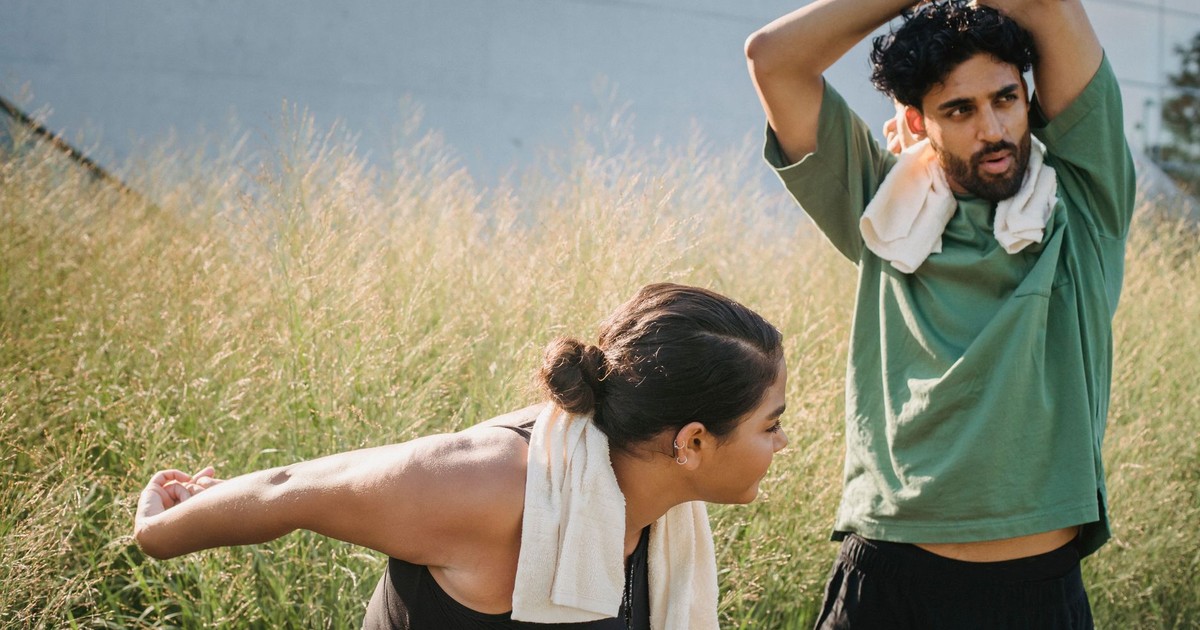 Man and woman stretching outdoors promoting a healthy lifestyle.