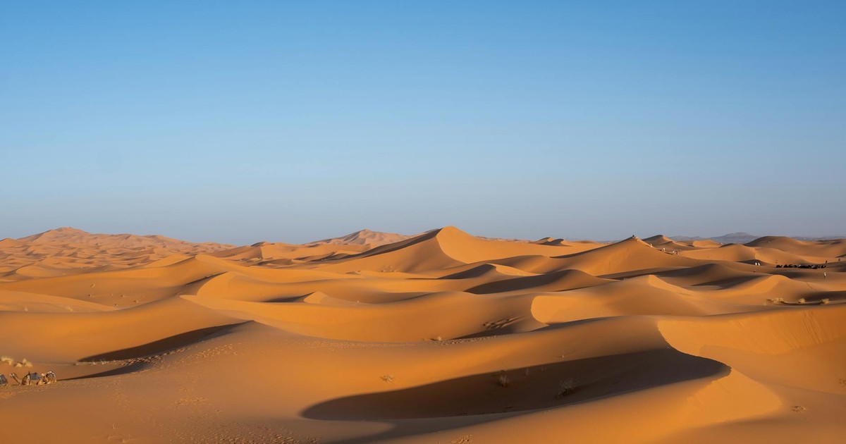 Breathtaking view of vast desert dunes with a bright blue sky, showcasing natural beauty and tranquility.