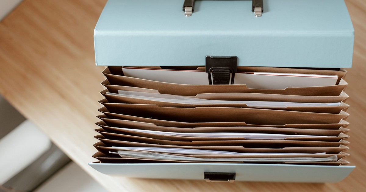 From above of briefcase for documents with papers placed on wooden table in daytime