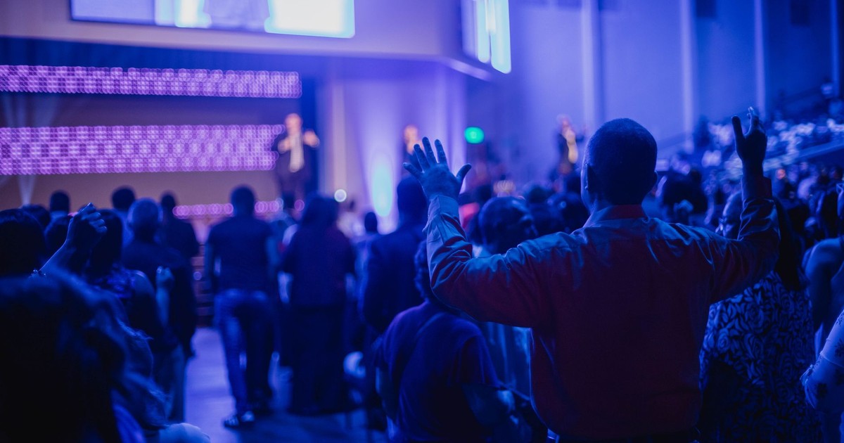 Excited audience enjoying a live concert with dynamic lighting and performers on stage.