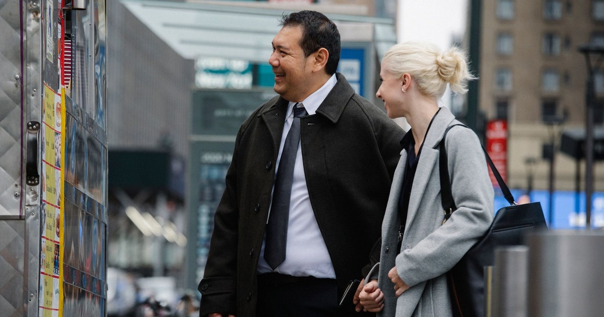 Mature man and woman in business clothes buying food in street van while chatting happily