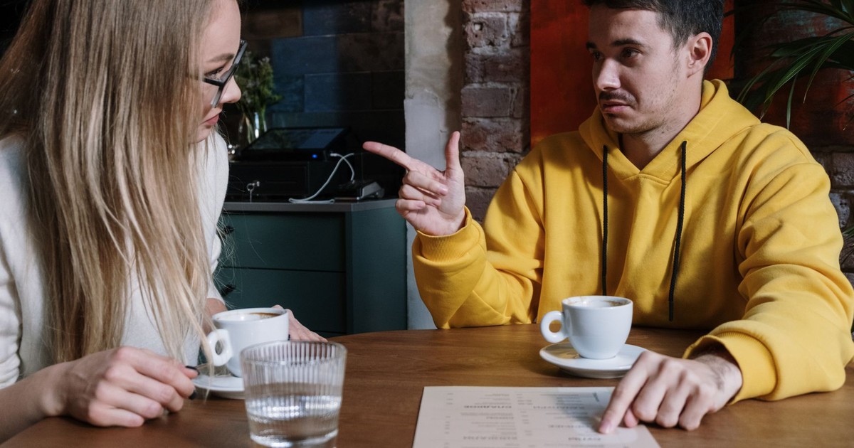 Two adults discussing over coffee and a menu at an urban cafe.