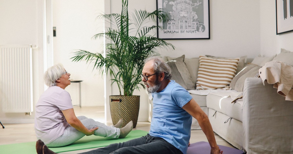 Senior couple doing yoga in a cozy living room, promoting health and active lifestyle.