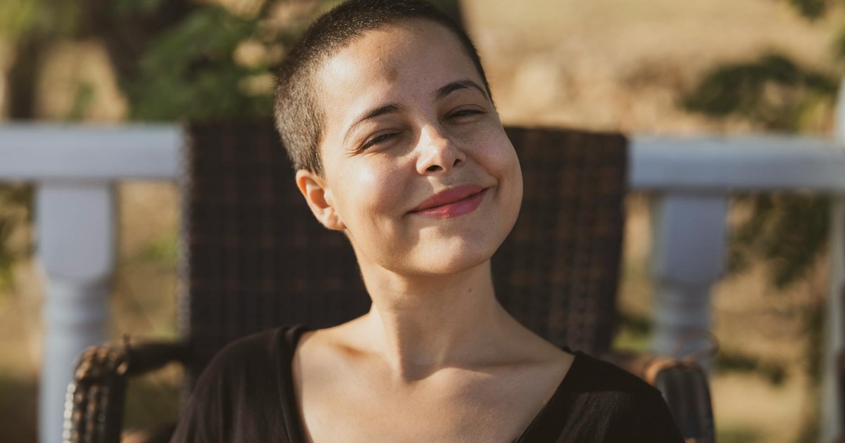 Portrait of a smiling woman enjoying a sunny day outdoors.