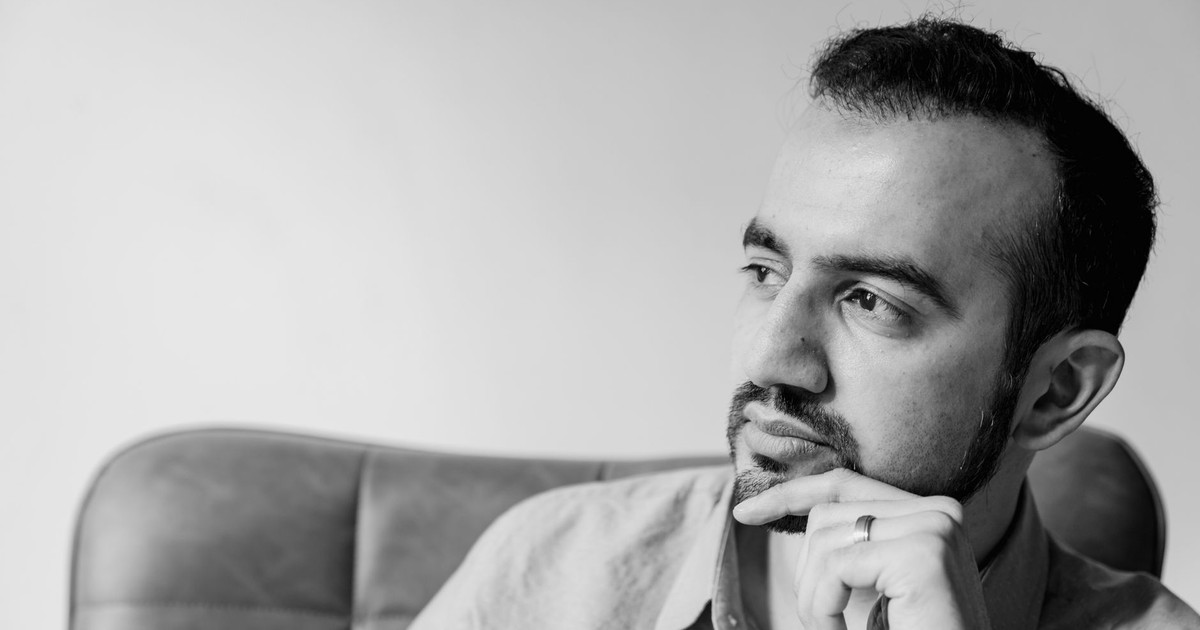 Thoughtful black and white portrait of a bearded man with facial hair, pondering indoors.