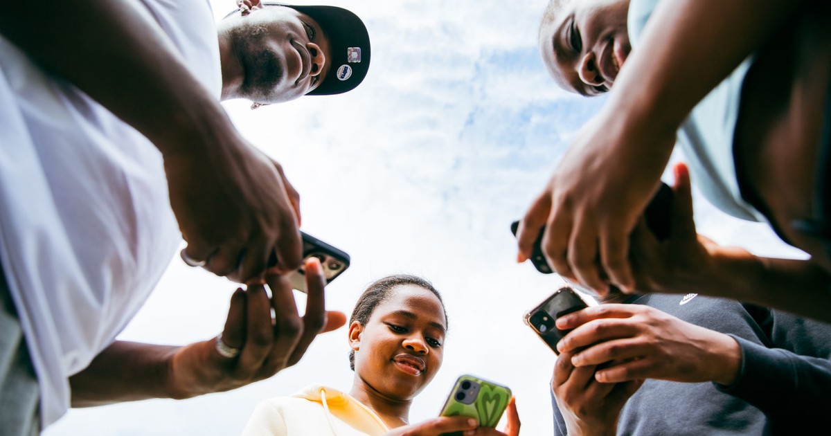 A diverse group of friends using smartphones together on a sunny day in Brussels.