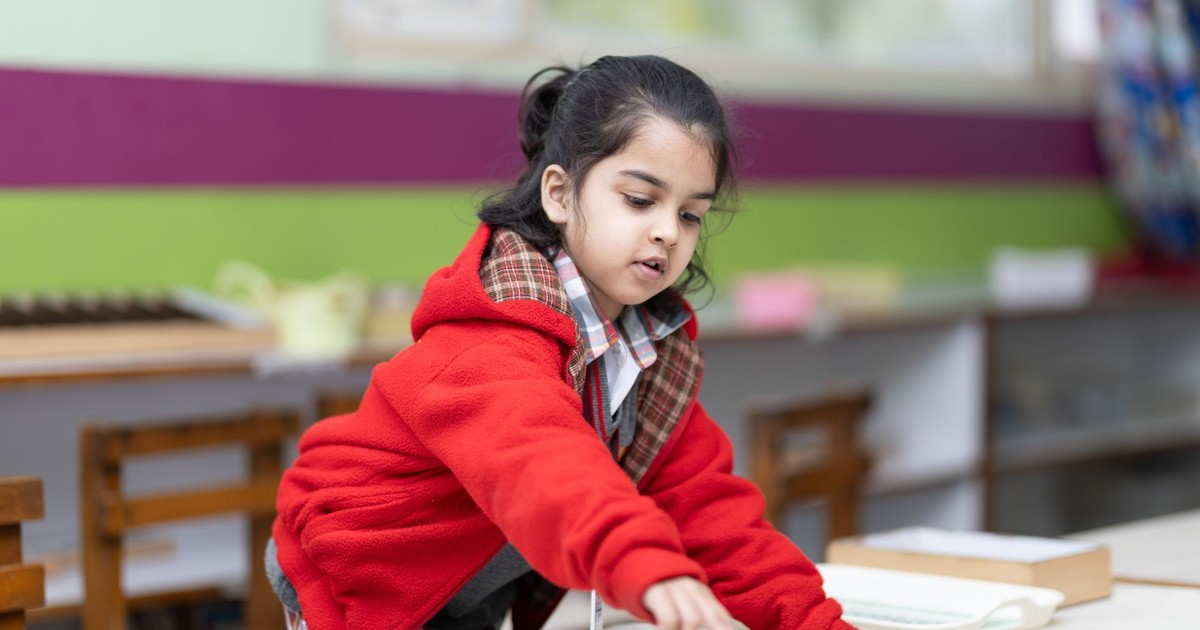 A young girl engages with educational materials in a vibrant classroom setting, promoting early learning.