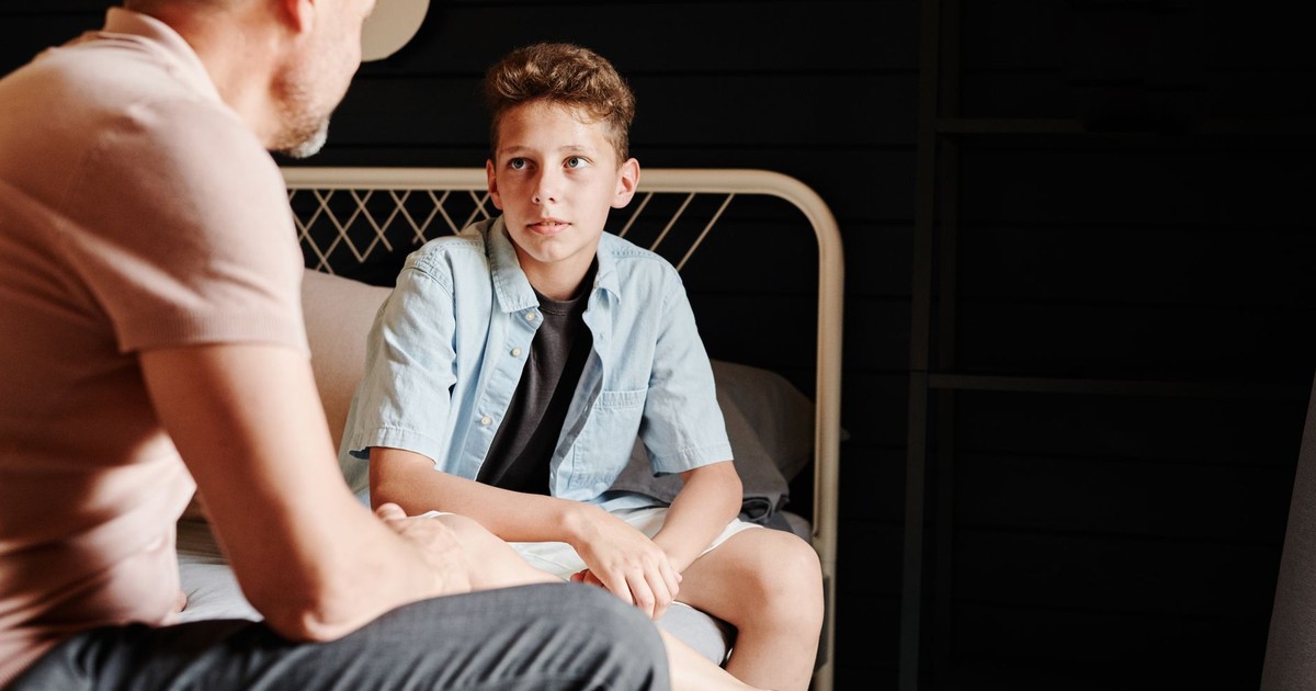 A father and son share a heartfelt conversation indoors, capturing a moment of bonding.