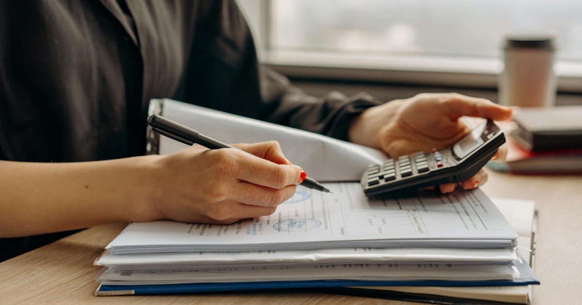 Close-up of person using a calculator with financial documents in an office.