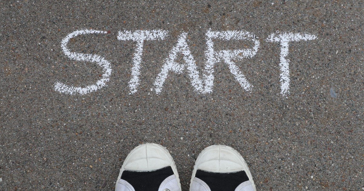 Close-up of sneakers and a 'START' chalk drawing on pavement, symbolizing new beginnings.