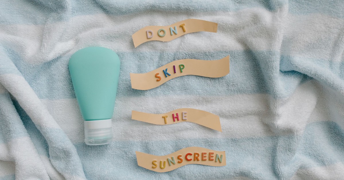 Flat lay of sunscreen bottle with message 'Don't skip the sunscreen' on a towel.