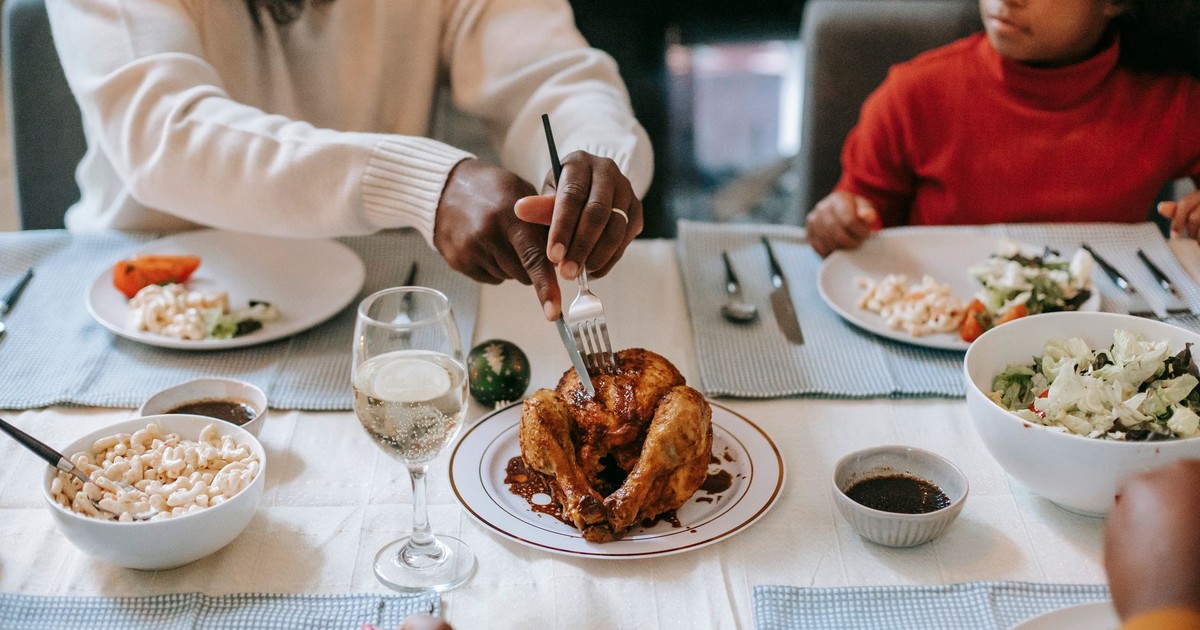 A cozy family dinner featuring roast chicken, salads, and macaroni on a beautifully set table.
