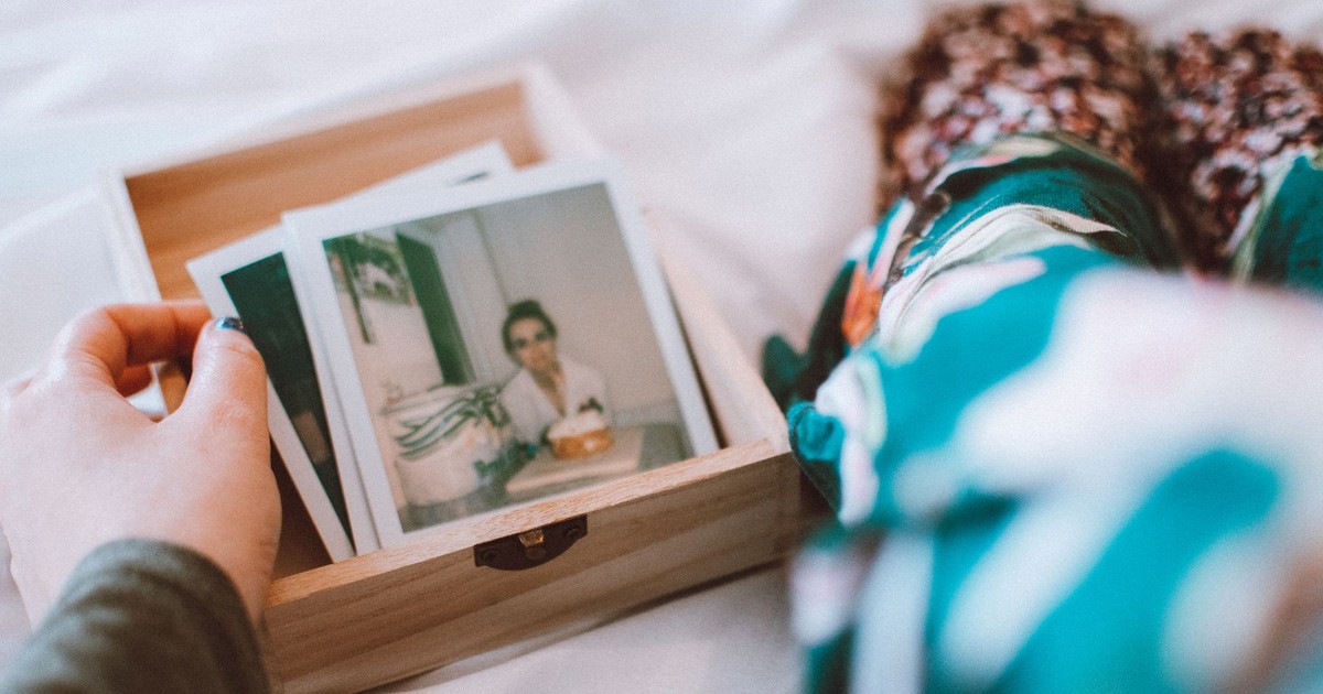 A woman reminisces as she browses vintage photographs indoors.