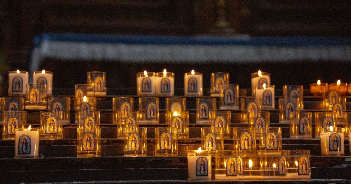 A serene display of lit devotional candles with Virgin Mary images inside a church, symbolizing faith and prayer.