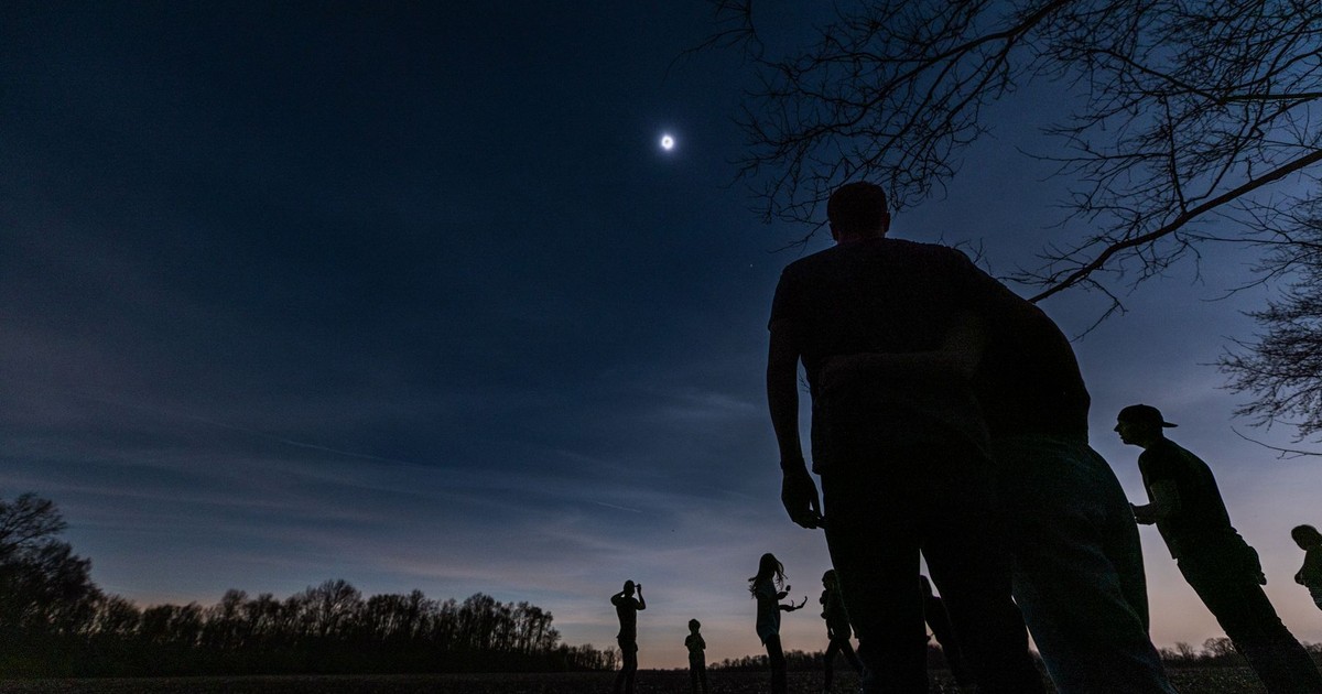 Group of people silhouetted against a moonlit sky, capturing a serene outdoor moment.