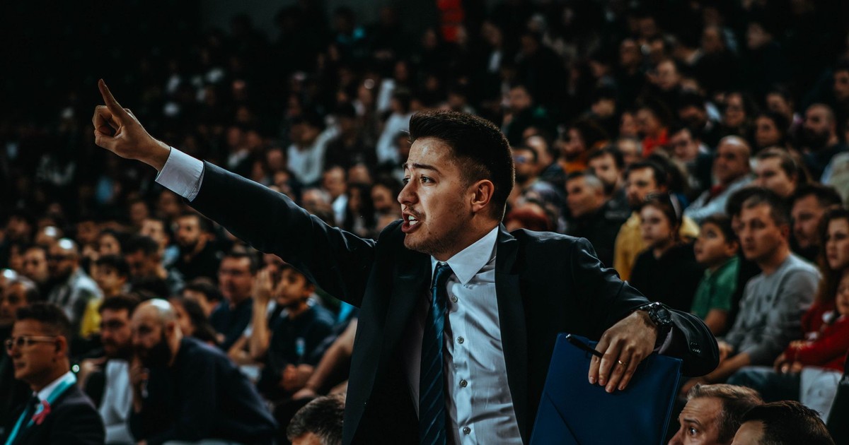 Motivated coach directing during a tense basketball game in a crowded arena.