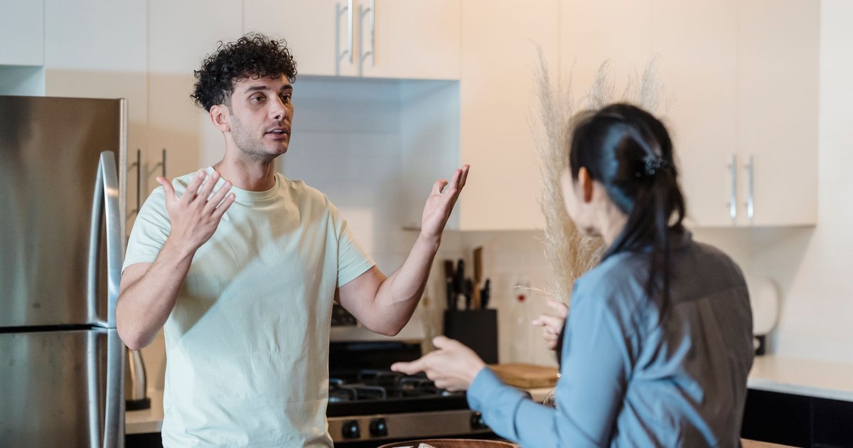 A couple in a tense conversation in a modern kitchen, expressing emotions.