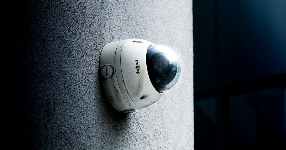 Close-up view of a dome security camera mounted on a concrete wall for surveillance.