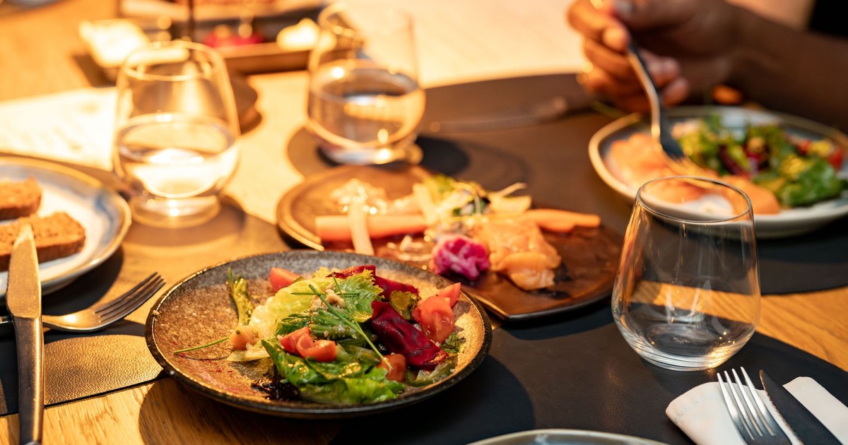 A beautifully set dinner table with gourmet salads and glassware, ideal for a classy dining experience.