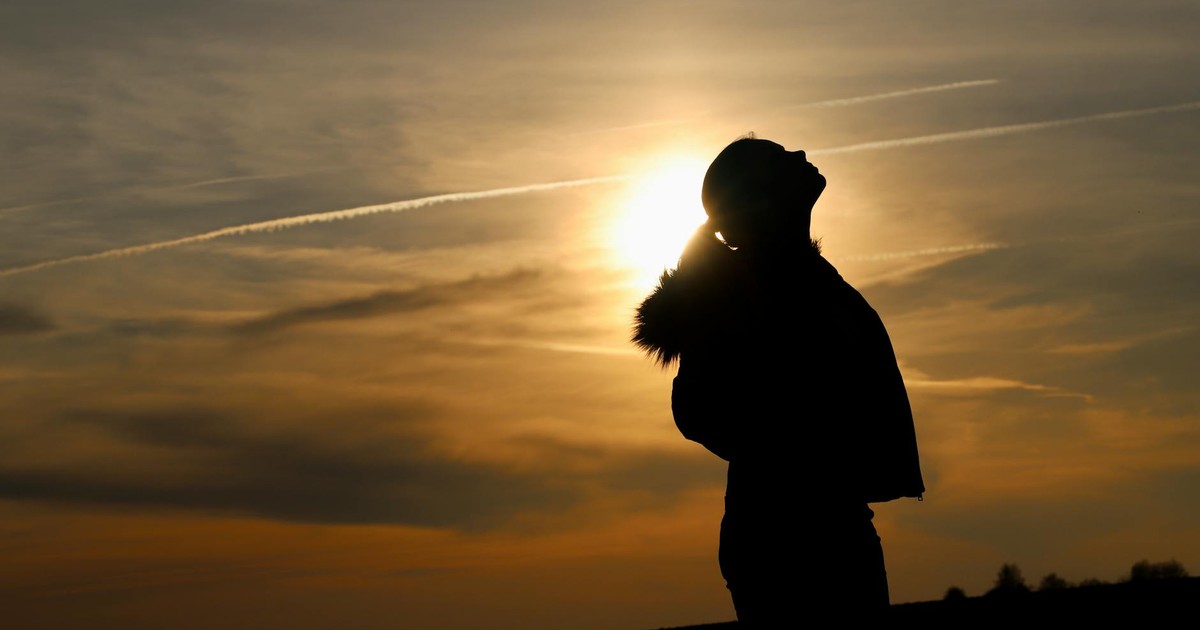 A beautiful silhouette of a woman looking up against the sunset sky, creating a serene and peaceful scene.