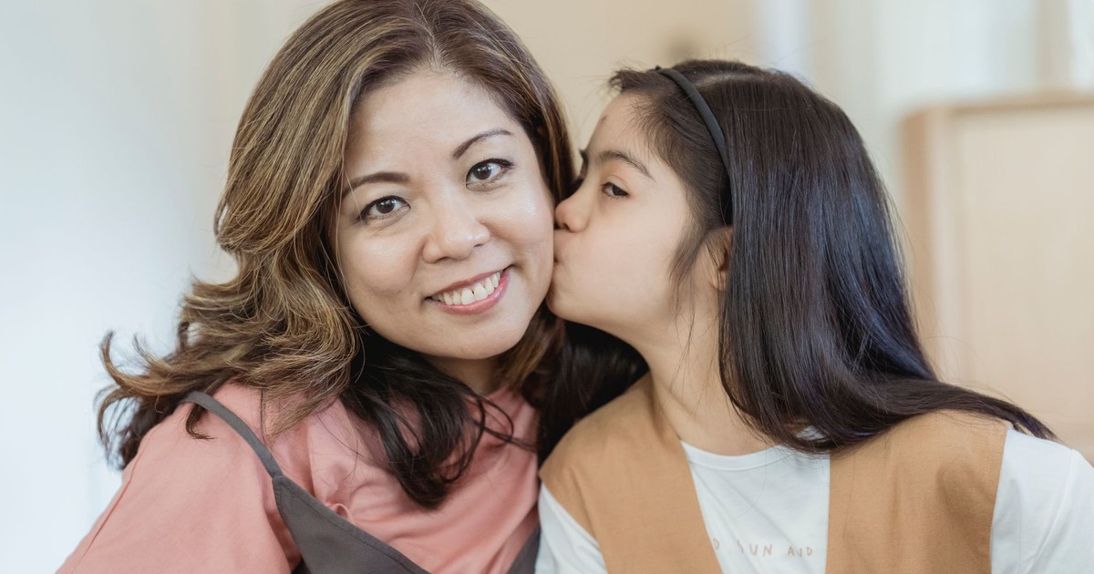 A cheerful daughter kisses her smiling mother, capturing a warm family bond.
